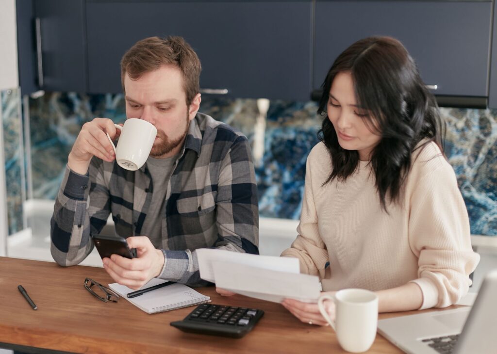 Person reviewing a home electricity bill beside a laptop and household energy devices